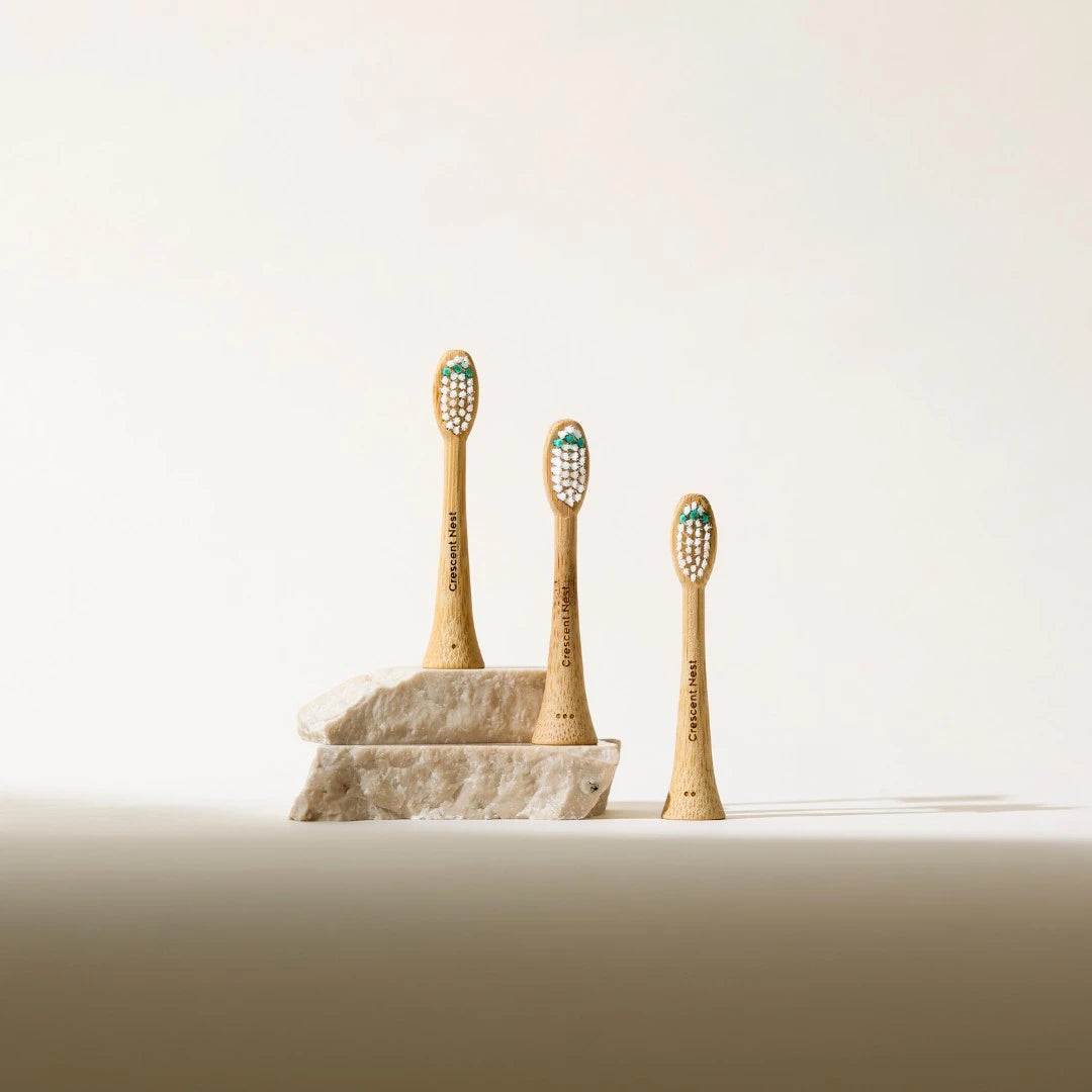Three bamboo toothbrushes on a stone stand with a plain background