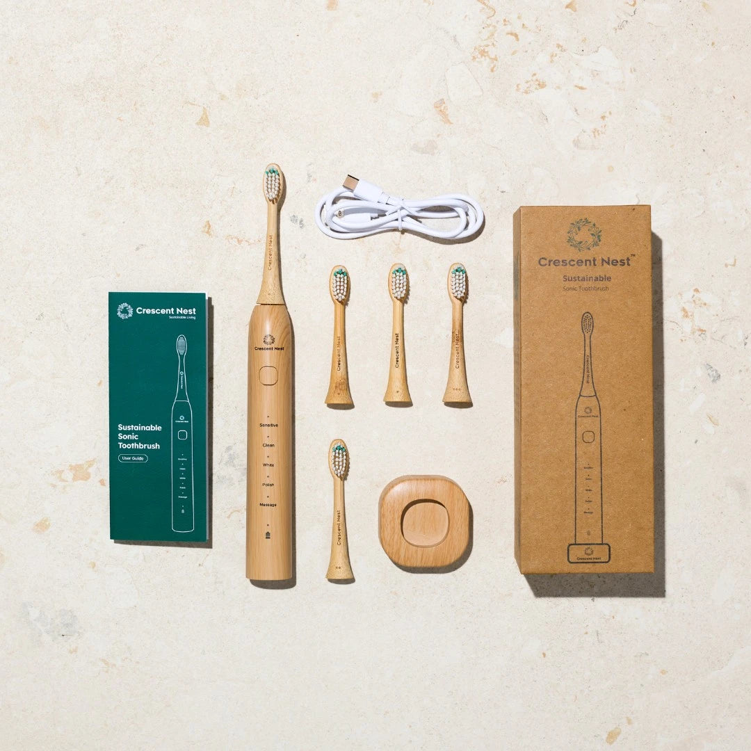Set of bamboo electric toothbrushes with packaging and charging cable on a beige surface