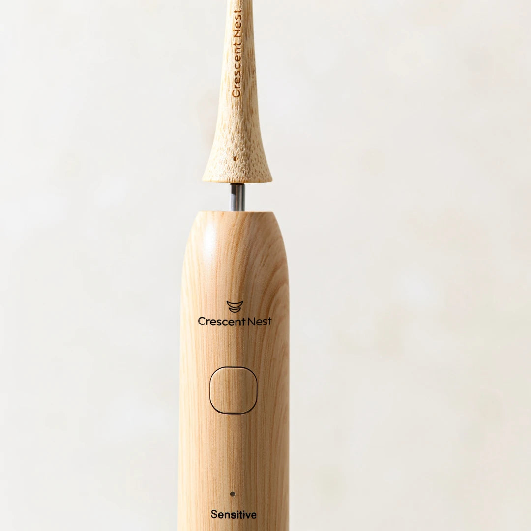 Close-up of the Crescent Nest bamboo electric toothbrush showing the detachable brush head and connection point.