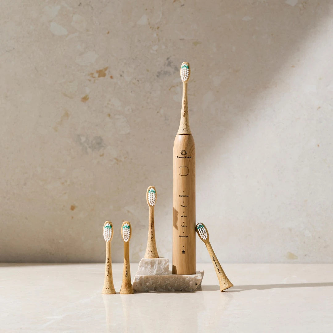 Set of bamboo electric toothbrushes with travel case on a textured surface