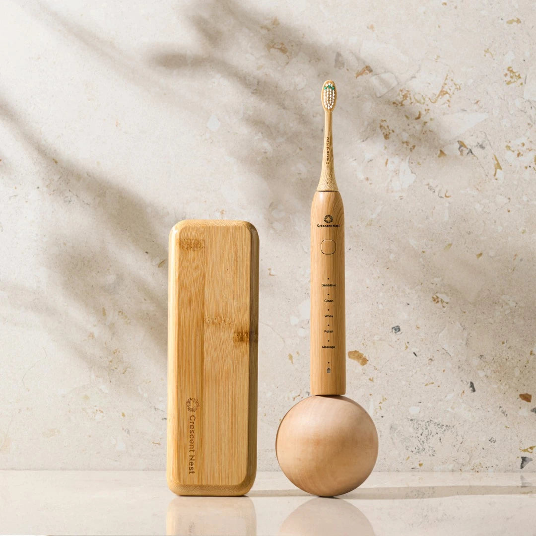 Wooden electric toothbrush and bamboo case on a light stone background