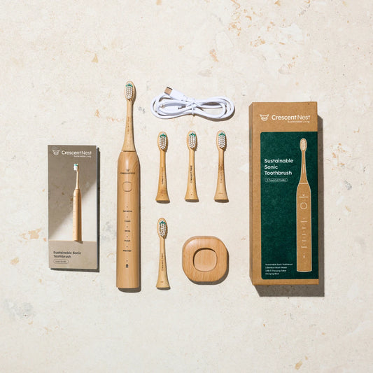 Crescent Nest Sustainable Sonic Toothbrush complete kit including bamboo toothbrush handle, four replacement brush heads, charging base, USB-C cable, user manual, and eco-friendly packaging.