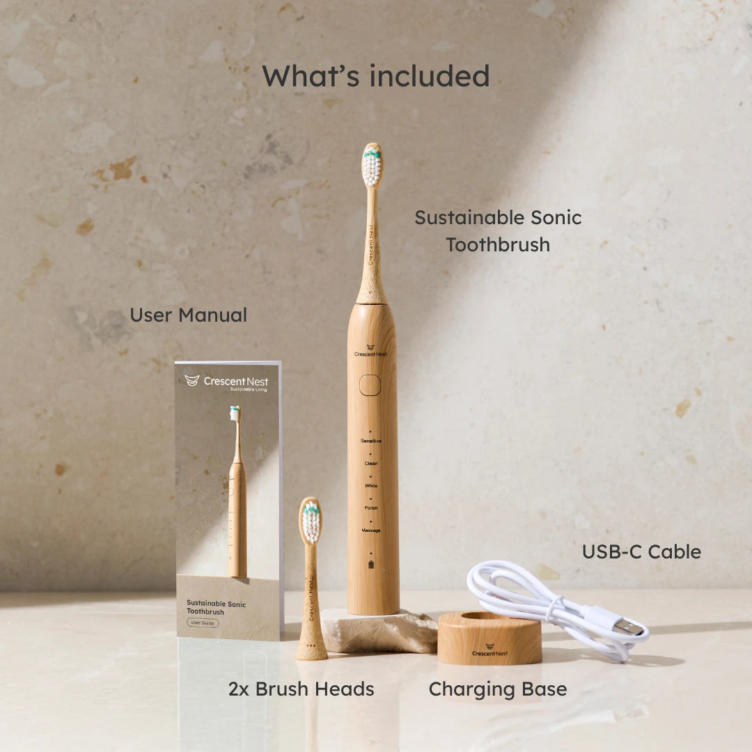 Crescent Nest Sustainable Sonic Toothbrush set showing what’s included: bamboo electric toothbrush, user manual, two brush heads, charging base, and USB-C cable.