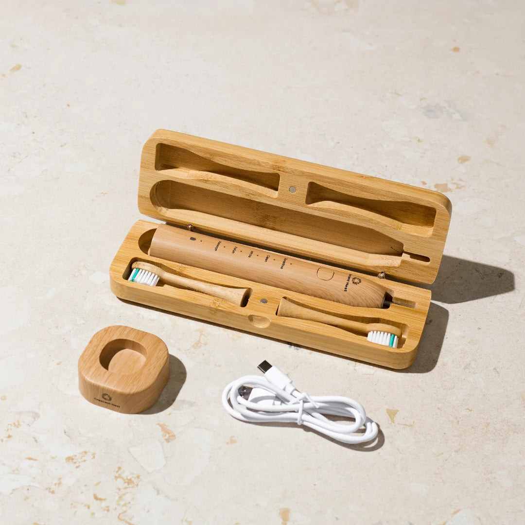 Bamboo toothbrush set with case, toothbrushes, and charging cable on a light surface