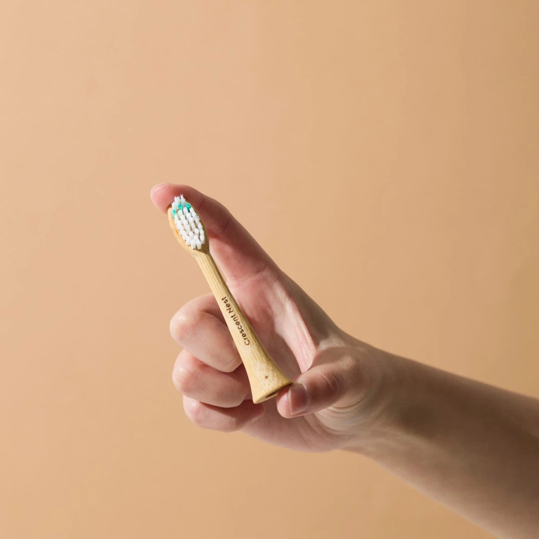 Hand holding a gold toothbrush with a beige background