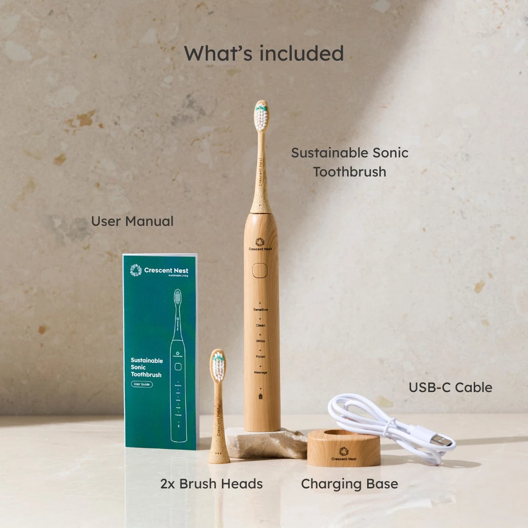 Sustainable sonic toothbrush set with packaging, brush heads, charging base, and USB-C cable on a neutral background.