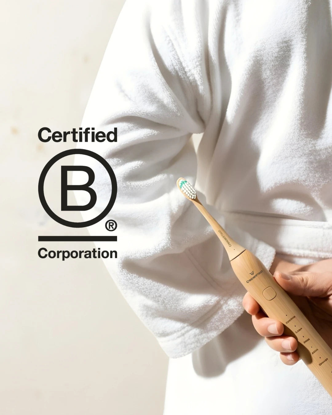 Person holding a crescent nest bamboo electric toothbrush with a Certified B Corporation logo in the corner.