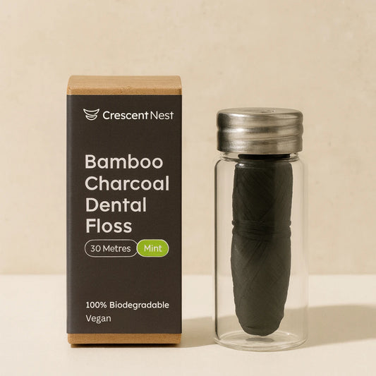 Bamboo charcoal dental floss in a glass container with packaging on a beige background