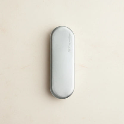 Crescent nest tongue scraper Medical Grade 304 travel case on a creamy background
