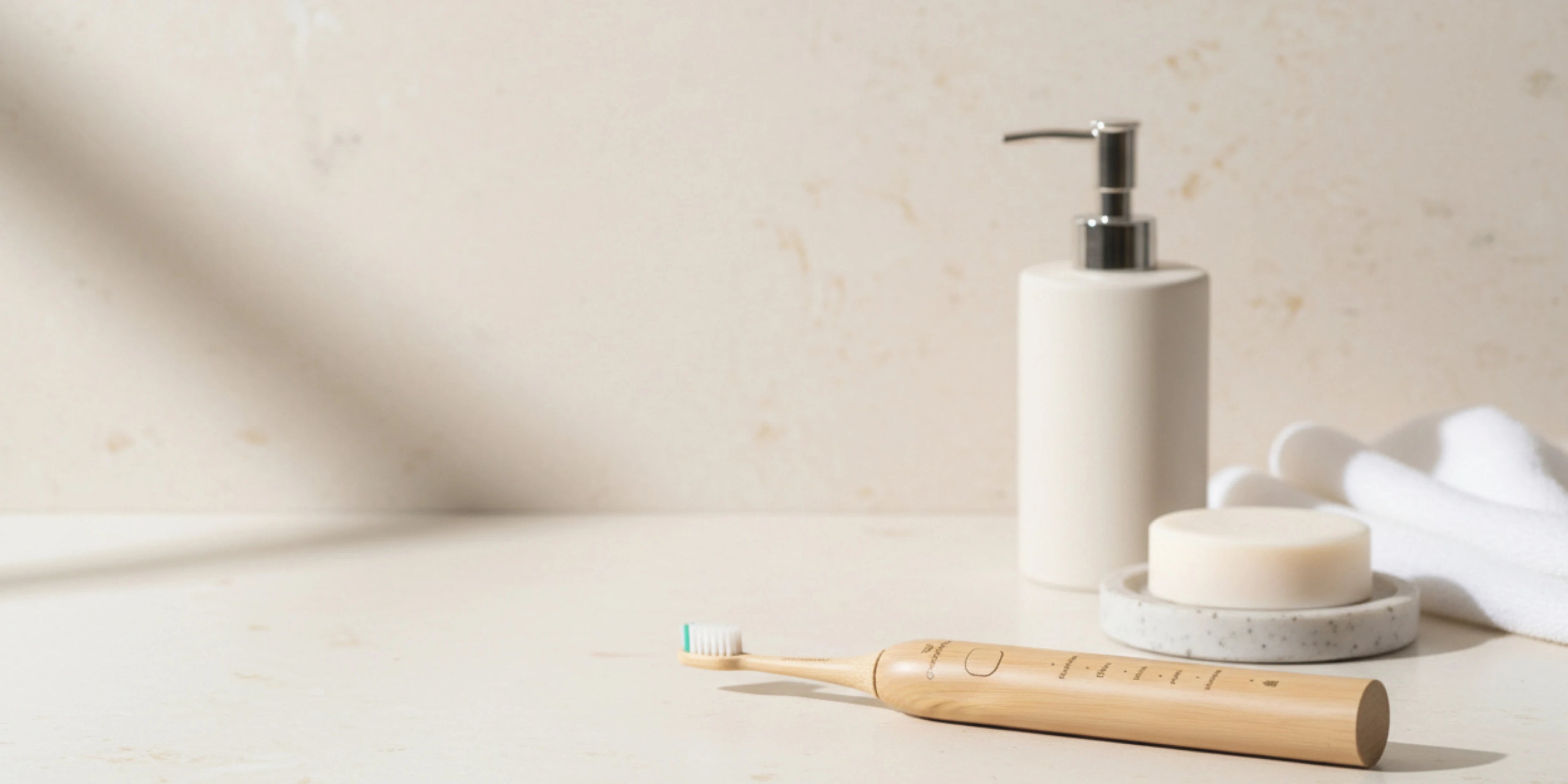 Crescent nest Bamboo toothbrush and soap dispenser on a light surface with a neutral background