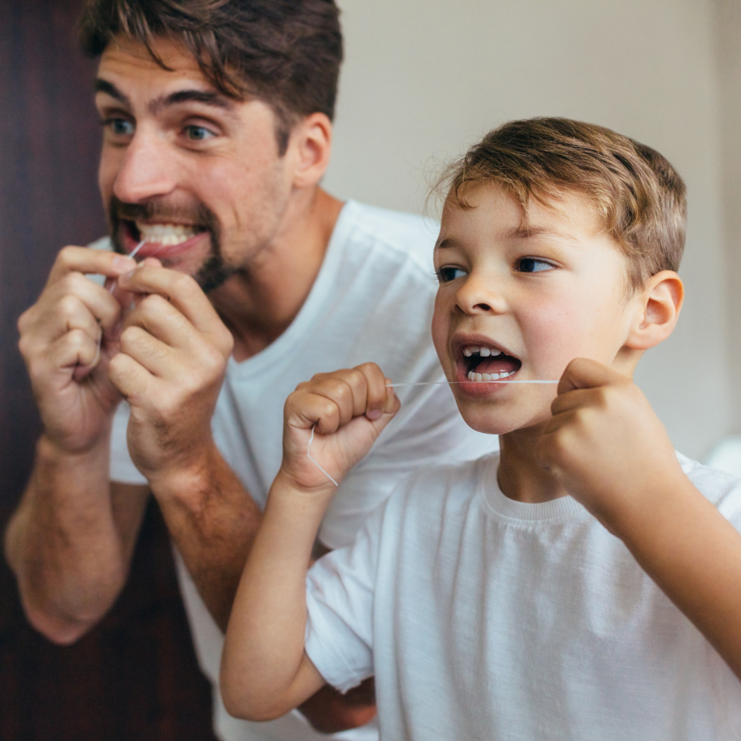 Man and child flossing their teeth together
