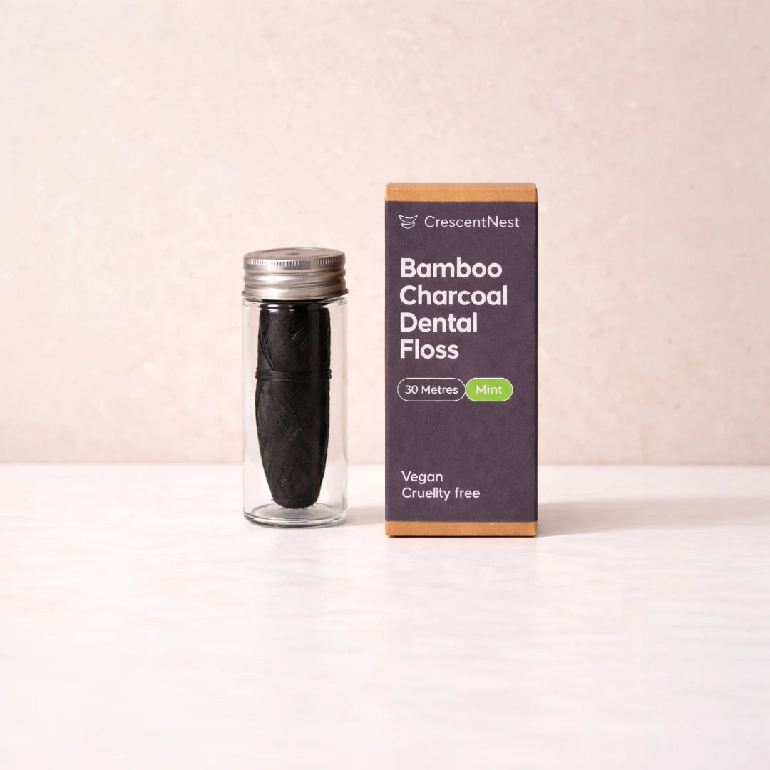 Bamboo charcoal dental floss in a clear container with packaging on a beige background