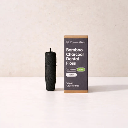 Black bamboo charcoal dental floss refill and its packaging on a beige background