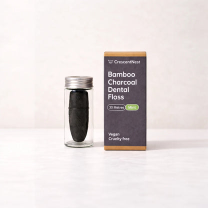 Bamboo charcoal dental floss in a clear container with packaging on a white background