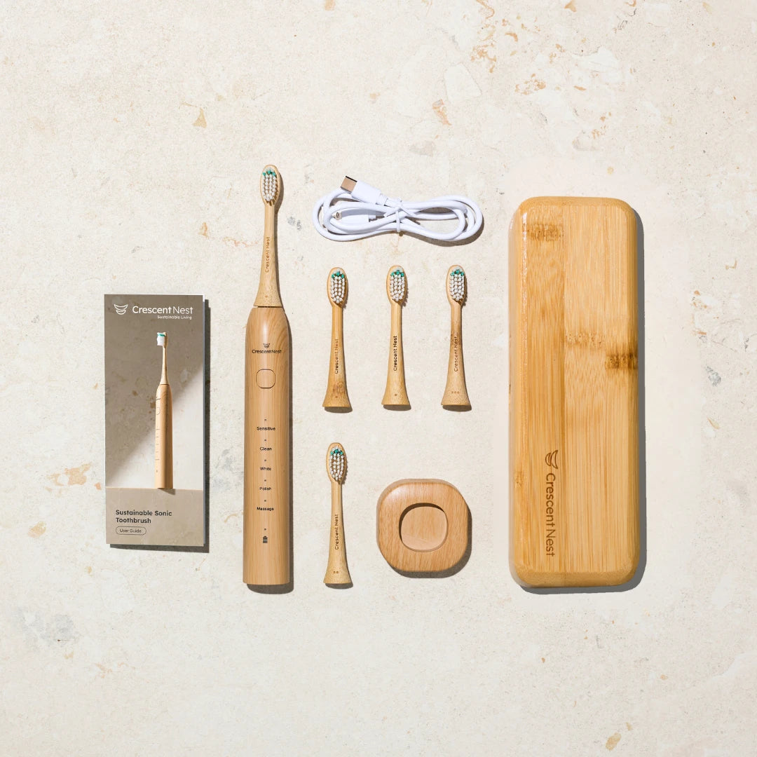 Crescent Nest complete bamboo toothbrush travel kit with electric toothbrush, brush heads, USB-C cable, charging base, user manual, and bamboo travel case.