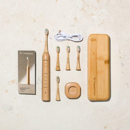 Crescent Nest complete bamboo toothbrush travel kit with electric toothbrush, brush heads, USB-C cable, charging base, user manual, and bamboo travel case.