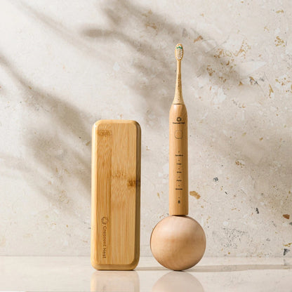 Wooden electric toothbrush and bamboo case on a light stone background