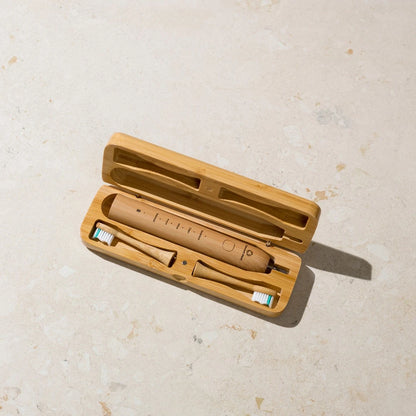 Wooden electric toothbrush with travel case on a light beige surface