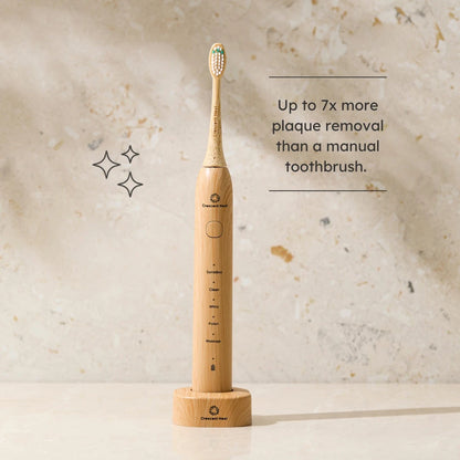 Wooden electric toothbrush on a textured beige background with text about plaque removal.