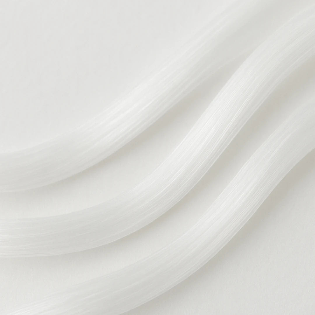 Close-up macro image of silky white polyester fibres flowing in smooth curved lines on a soft neutral background.